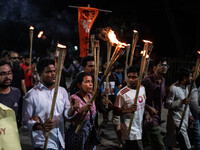 People hold a procession with torches to protest the recent violent clashes and counter-clashes between the local indigenous population and...