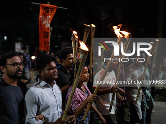 People hold a procession with torches to protest the recent violent clashes and counter-clashes between the local indigenous population and...