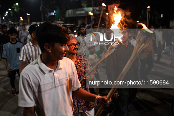 People hold a procession with torches to protest the recent violent clashes and counter-clashes between the local indigenous population and...