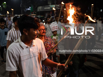 People hold a procession with torches to protest the recent violent clashes and counter-clashes between the local indigenous population and...