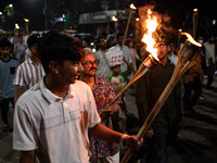 People hold a procession with torches to protest the recent violent clashes and counter-clashes between the local indigenous population and...