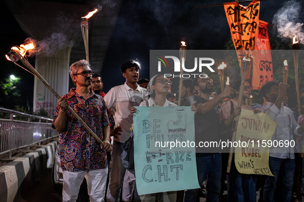 People hold a procession with torches to protest the recent violent clashes and counter-clashes between the local indigenous population and...