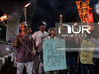 People hold a procession with torches to protest the recent violent clashes and counter-clashes between the local indigenous population and...