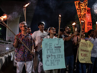 People hold a procession with torches to protest the recent violent clashes and counter-clashes between the local indigenous population and...