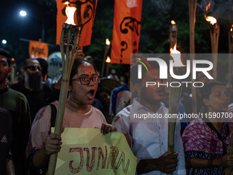 People hold a procession with torches to protest the recent violent clashes and counter-clashes between the local indigenous population and...