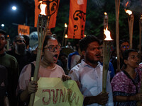 People hold a procession with torches to protest the recent violent clashes and counter-clashes between the local indigenous population and...