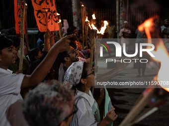 People hold a procession with torches to protest the recent violent clashes and counter-clashes between the local indigenous population and...