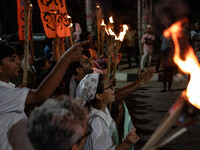 People hold a procession with torches to protest the recent violent clashes and counter-clashes between the local indigenous population and...