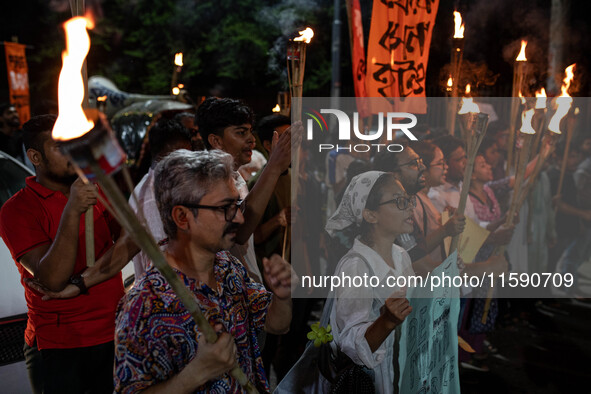 People hold a procession with torches to protest the recent violent clashes and counter-clashes between the local indigenous population and...