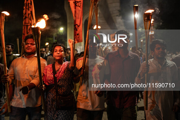 People hold a procession with torches to protest the recent violent clashes and counter-clashes between the local indigenous population and...