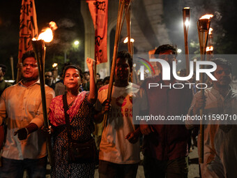 People hold a procession with torches to protest the recent violent clashes and counter-clashes between the local indigenous population and...