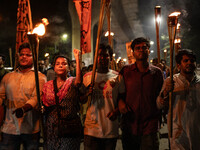 People hold a procession with torches to protest the recent violent clashes and counter-clashes between the local indigenous population and...