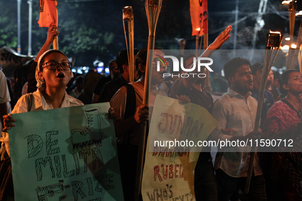 People hold a procession with torches to protest the recent violent clashes and counter-clashes between the local indigenous population and...