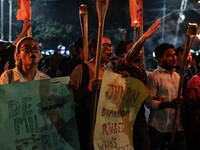 People hold a procession with torches to protest the recent violent clashes and counter-clashes between the local indigenous population and...