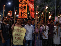 People hold a procession with torches to protest the recent violent clashes and counter-clashes between the local indigenous population and...