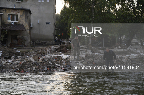 A man enters into the Morawka river to clean his boots after the flood left debris and damaged houses in Stronie Slaskie, Poland on Septembe...