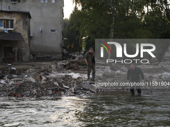 A man enters into the Morawka river to clean his boots after the flood left debris and damaged houses in Stronie Slaskie, Poland on Septembe...