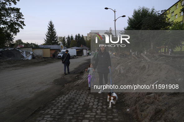 A woman and her daughter walk their dog amongst debris left by the flood in Stronie Slaskie, Poland on September 20, 2024. 