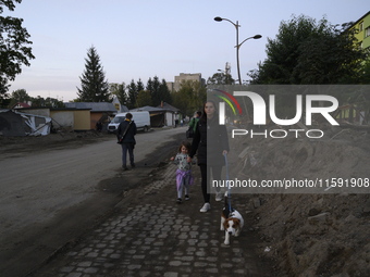 A woman and her daughter walk their dog amongst debris left by the flood in Stronie Slaskie, Poland on September 20, 2024. (