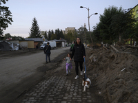 A woman and her daughter walk their dog amongst debris left by the flood in Stronie Slaskie, Poland on September 20, 2024. (