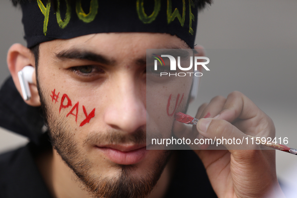 A Nepali activist paints his face with slogans calling for climate justice during a march to mark Global Week of Action for Peace and Climat...