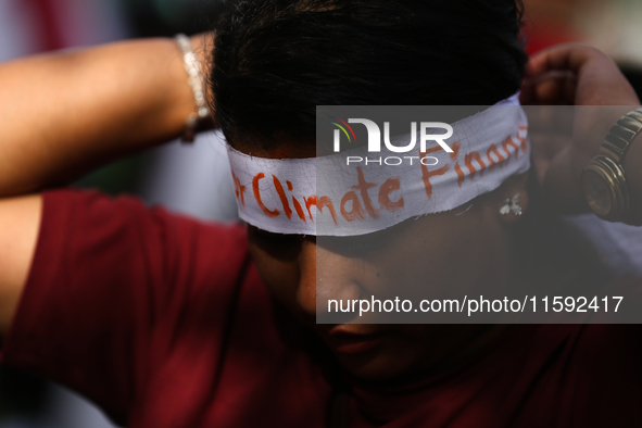 A Nepali activist ties a headband with slogans calling for climate justice during a march to mark Global Week of Action for Peace and Climat...