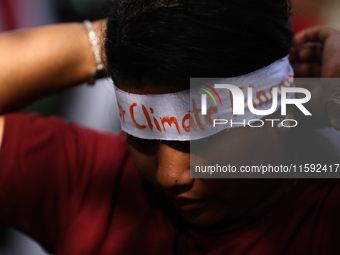 A Nepali activist ties a headband with slogans calling for climate justice during a march to mark Global Week of Action for Peace and Climat...