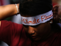 A Nepali activist ties a headband with slogans calling for climate justice during a march to mark Global Week of Action for Peace and Climat...