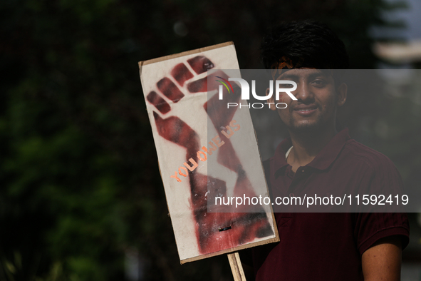 A Nepali activist poses for a photo displaying a placard calling for climate justice during a march to mark Global Week of Action for Peace...