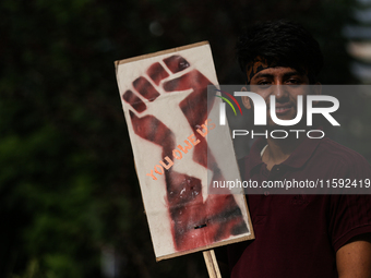 A Nepali activist poses for a photo displaying a placard calling for climate justice during a march to mark Global Week of Action for Peace...