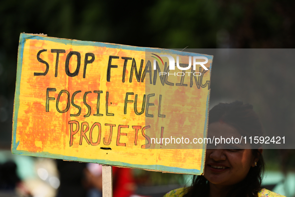 A Nepali activist holds a placard displaying slogans calling for climate justice during a march to mark Global Week of Action for Peace and...