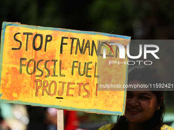 A Nepali activist holds a placard displaying slogans calling for climate justice during a march to mark Global Week of Action for Peace and...