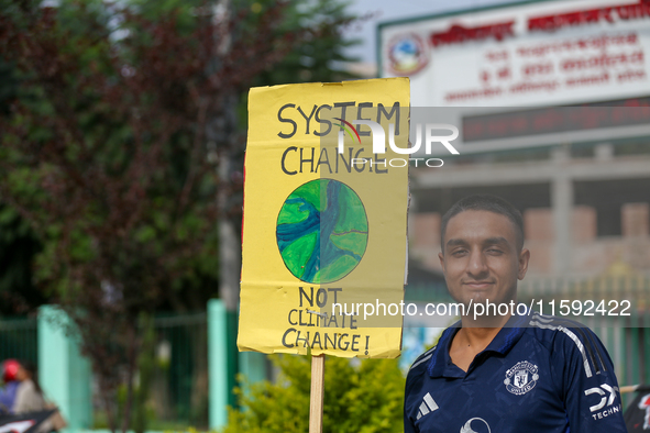 A Nepali activist holds a placard displaying slogans calling for climate justice during a march to mark Global Week of Action for Peace and...