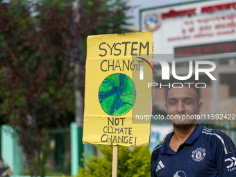 A Nepali activist holds a placard displaying slogans calling for climate justice during a march to mark Global Week of Action for Peace and...