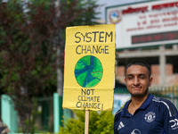 A Nepali activist holds a placard displaying slogans calling for climate justice during a march to mark Global Week of Action for Peace and...