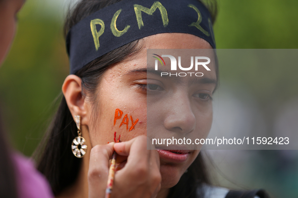 A Nepali activist paints her face with slogans calling for climate justice during a march to mark Global Week of Action for Peace and Climat...