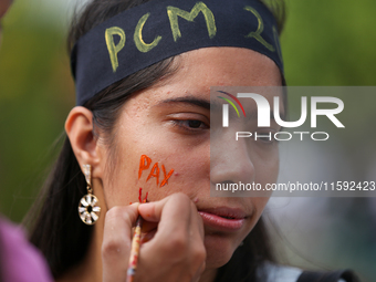 A Nepali activist paints her face with slogans calling for climate justice during a march to mark Global Week of Action for Peace and Climat...