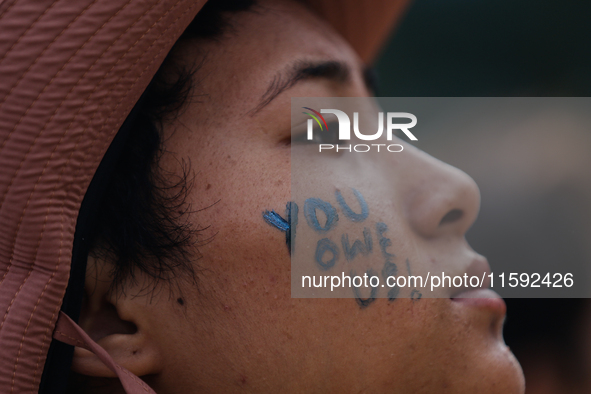 A Nepali activist paints her face with slogans calling for climate justice during a march to mark Global Week of Action for Peace and Climat...