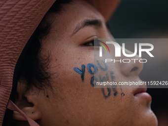 A Nepali activist paints her face with slogans calling for climate justice during a march to mark Global Week of Action for Peace and Climat...