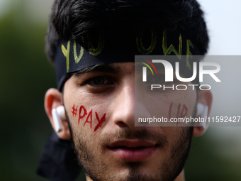 A Nepali activist poses for a photo with slogans calling for climate justice on his face during a march to mark Global Week of Action for Pe...