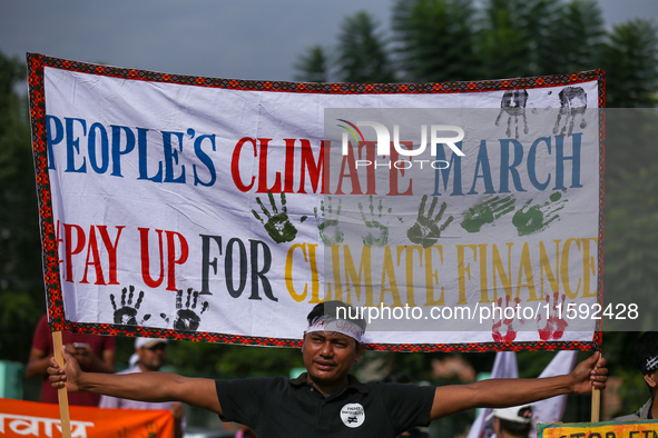 A Nepali activist holds a banner displaying slogans calling for climate justice during a march to mark Global Week of Action for Peace and C...