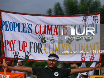 A Nepali activist holds a banner displaying slogans calling for climate justice during a march to mark Global Week of Action for Peace and C...