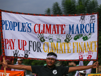 A Nepali activist holds a banner displaying slogans calling for climate justice during a march to mark Global Week of Action for Peace and C...