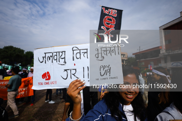 A Nepali activist displays a slogan calling for climate justice during a march to mark the Global Week of Action for Peace and Climate Justi...