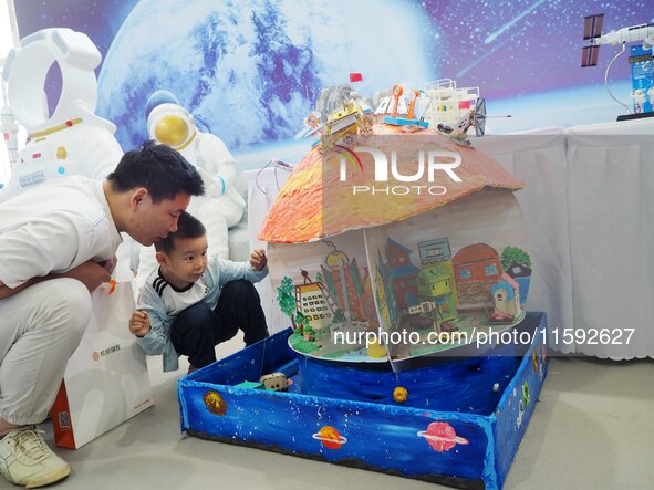 Visitors look at a model of a Mars home made by primary school students during the 2024 National Science Popularization Day in Beijing, Chin...