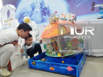 Visitors look at a model of a Mars home made by primary school students during the 2024 National Science Popularization Day in Beijing, Chin...