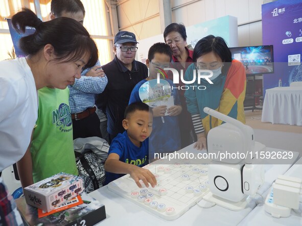 A child plays with a chess robot during the 2024 National Science Popularization Day in Beijing, China, on September 21, 2024. 