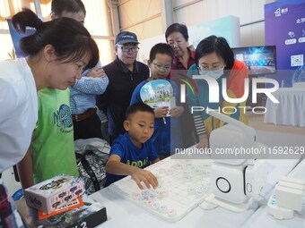 A child plays with a chess robot during the 2024 National Science Popularization Day in Beijing, China, on September 21, 2024. (