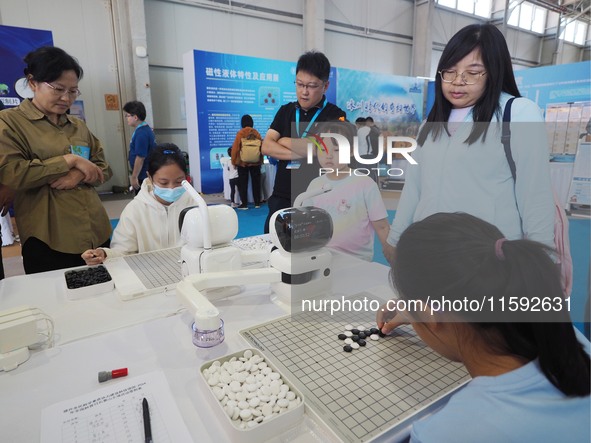 A child plays Weiqi with a robot during the 2024 National Science Popularization Day in Beijing, China, on September 21, 2024. 