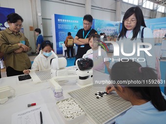 A child plays Weiqi with a robot during the 2024 National Science Popularization Day in Beijing, China, on September 21, 2024. (